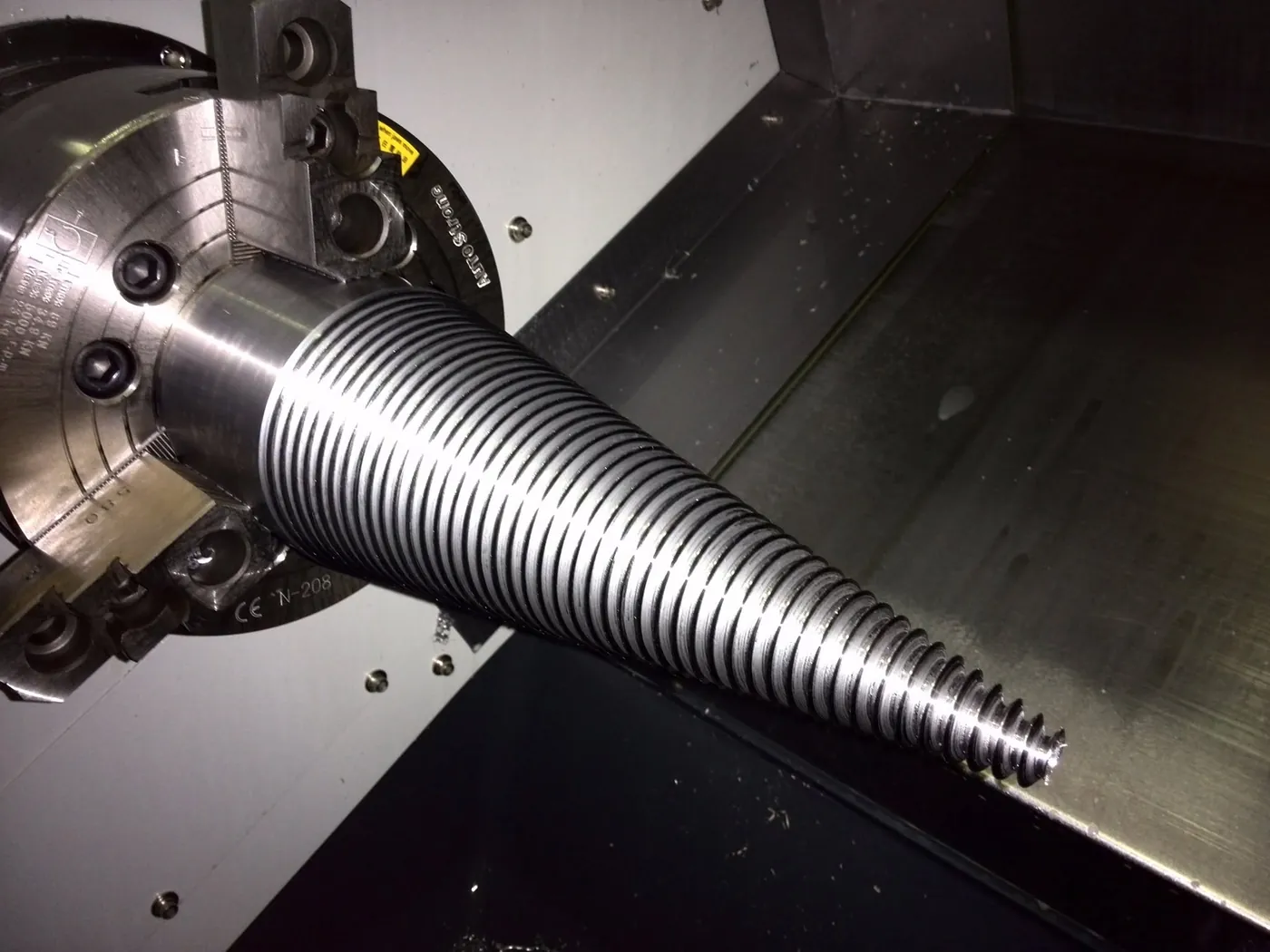 Tapered threaded cone held in the chuck of a CNC lathe