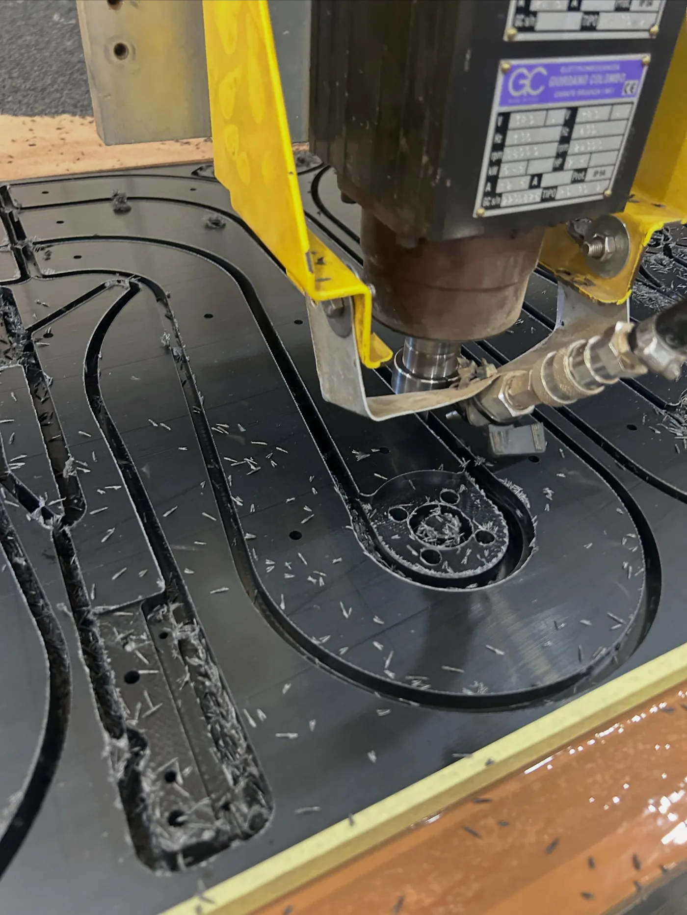 CNC router cutting a profile from black engineering plastic sheet