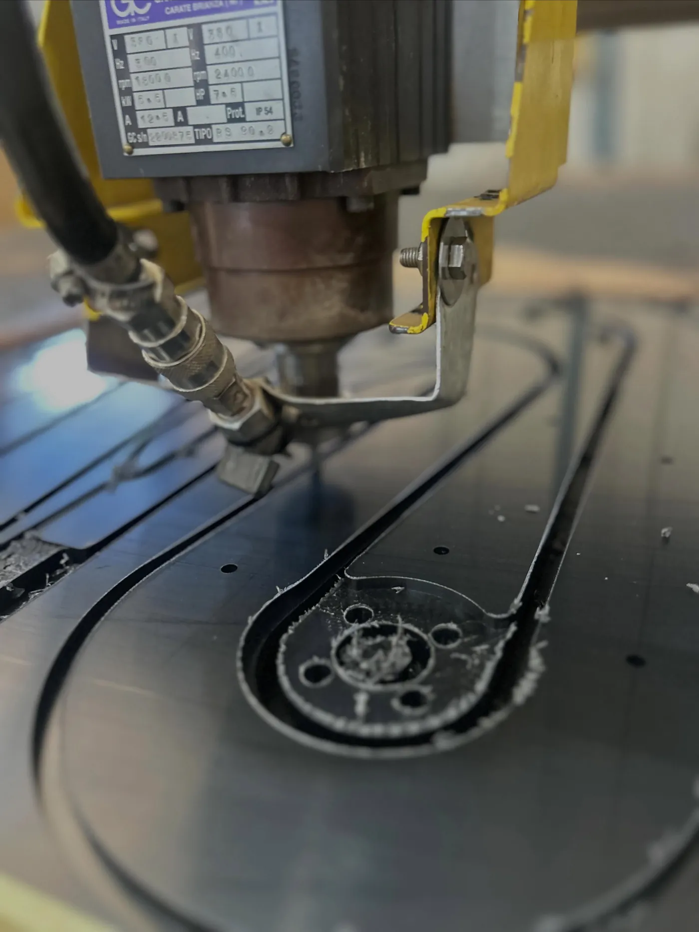 Spindle of a CNC router cutting slots in black plastic sheet