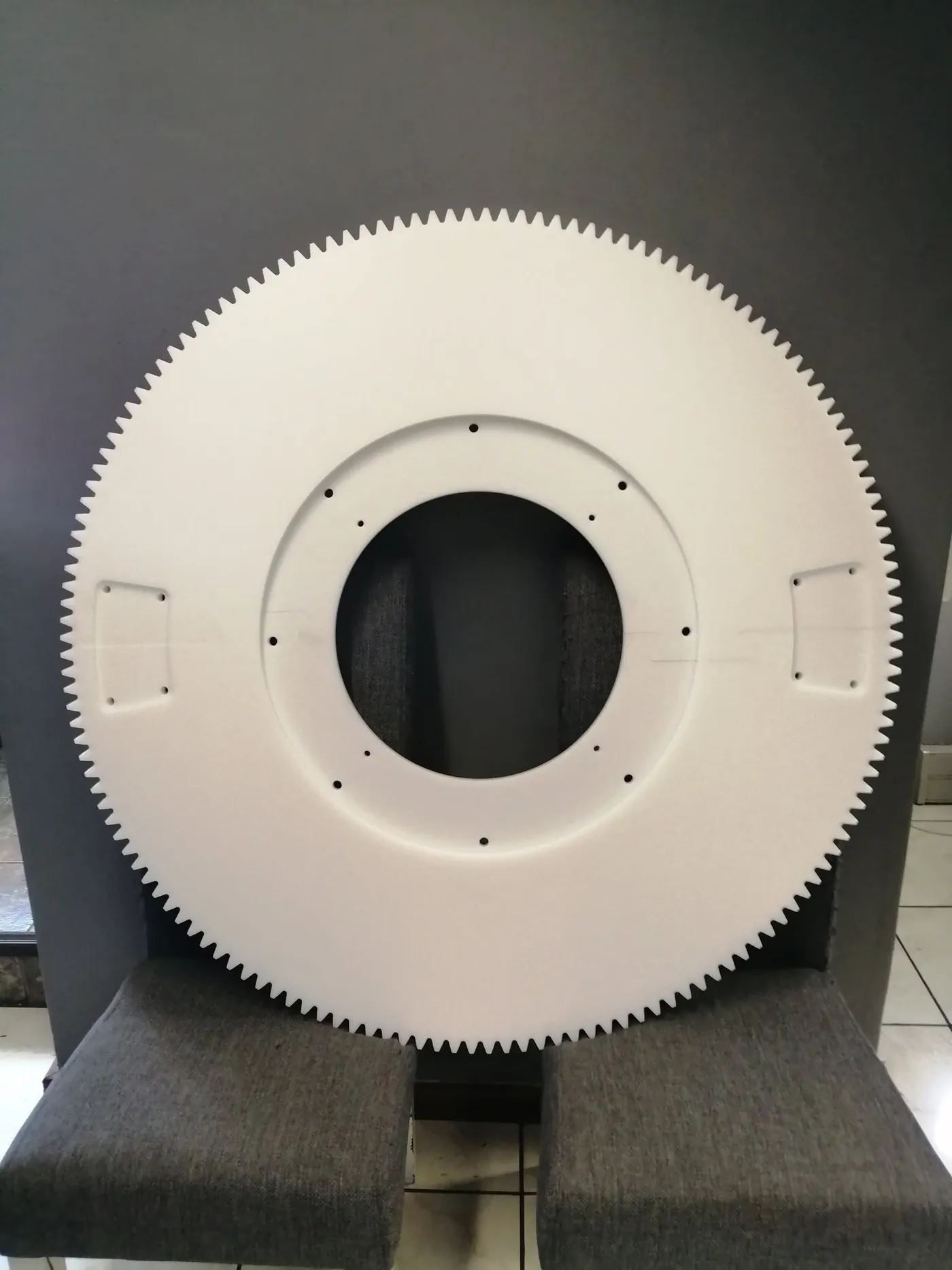 Large white engineering plastic gear wheel with fine cut teeth and a drilled bolt circle